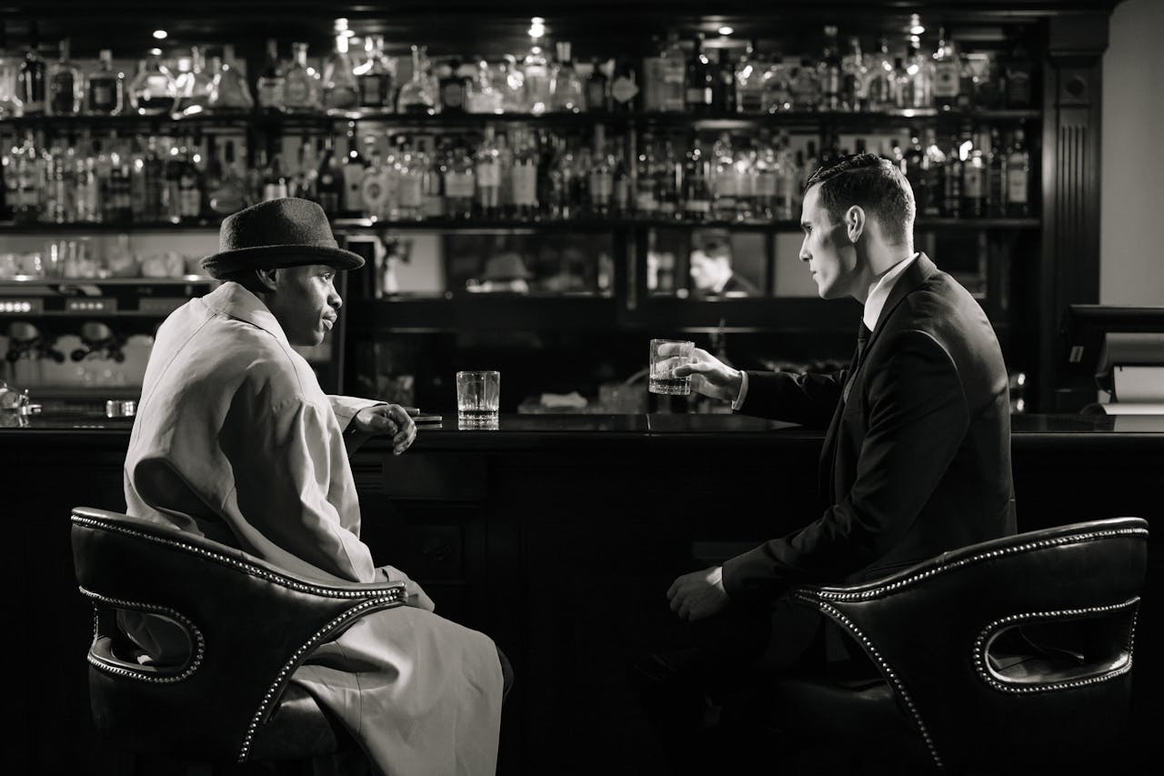 home-services-01 A cinematic, noir-style meeting in a dimly lit bar with a tense atmosphere.